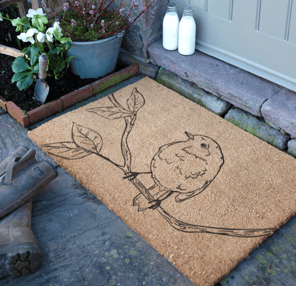Doormat with a bird design on a stone step outside a house.
