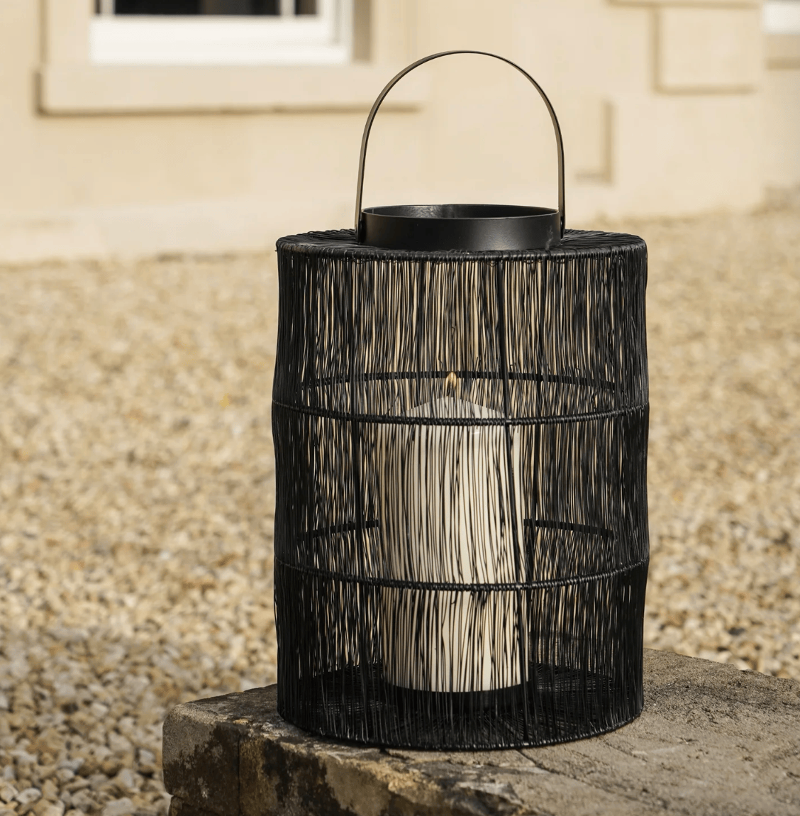 Black woven lantern on a stone surface with a neutral background