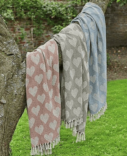 Three patterned Heart  throws draped over a tree outdoors by Walton & Co