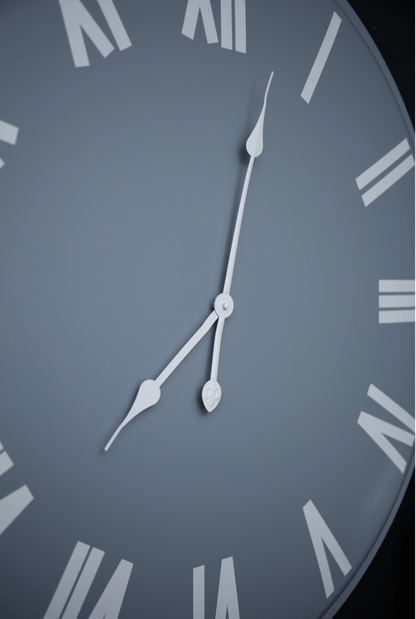 Close-up of a clock face with Roman numerals on a gray background