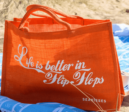 Orange tote bag with 'Life is better in Flip Flops' text on a beach setting