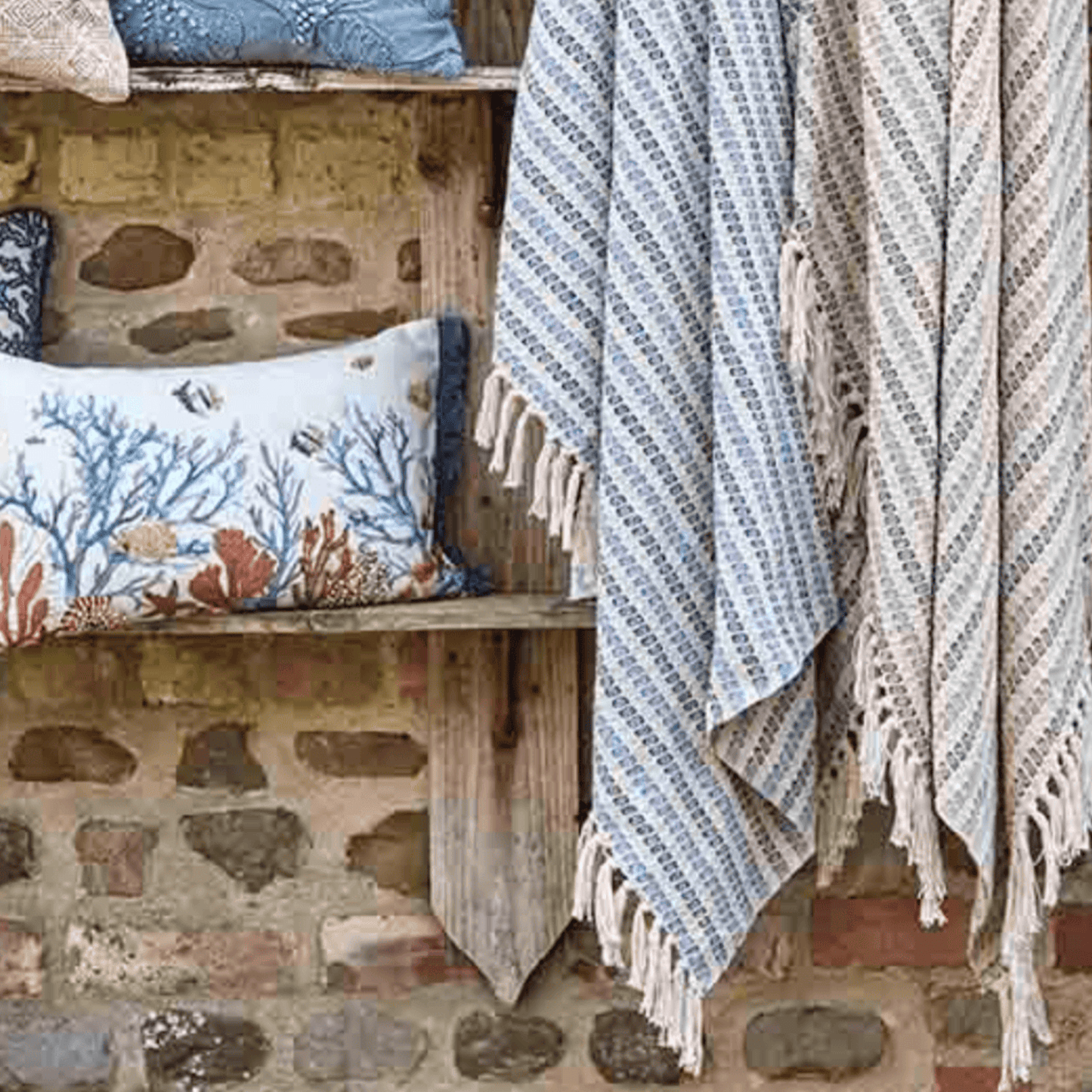 Textile items including a towel and pillows on a stone wall background