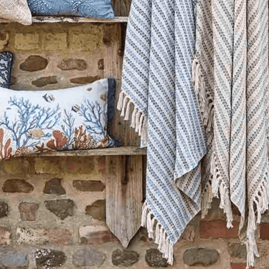 Textile items including a towel and pillows on a stone wall background