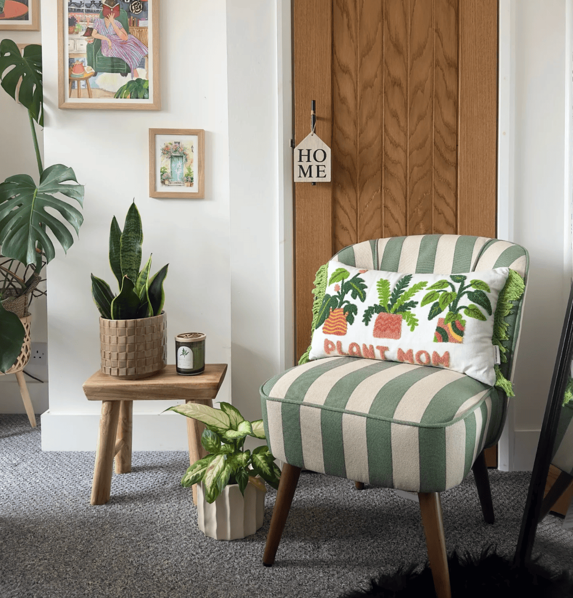 Green and white striped armchair with a 'Plant Mom' pillow in a room with plants and a wooden door.