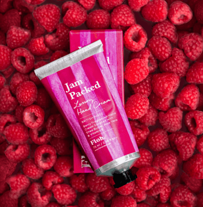 Hand cream tube labeled 'Jam Packed' on a bed of raspberries