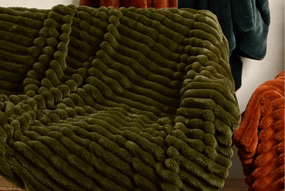 Green textured blanket draped over a surface with a blurred background