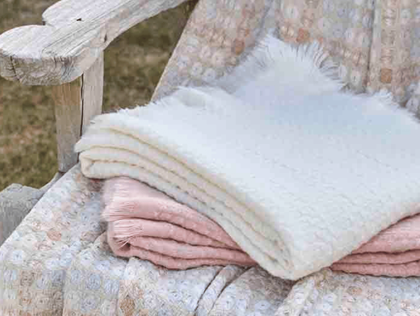 Folded blankets in pastel colors on a wooden bench outdoors