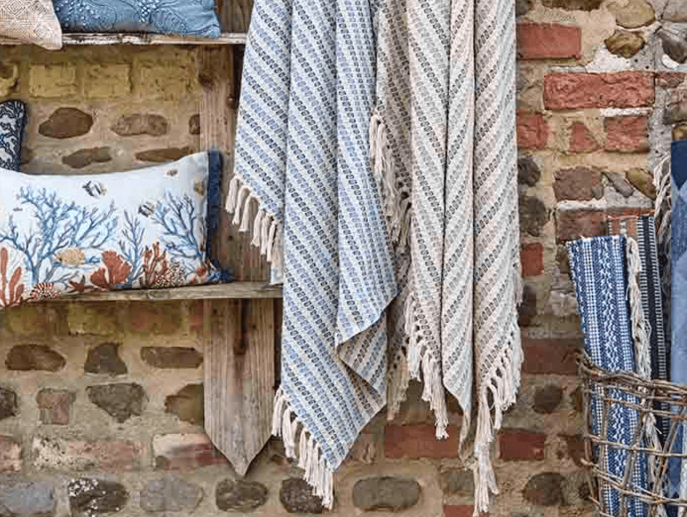 Textile items including a towel and pillows against a stone wall.