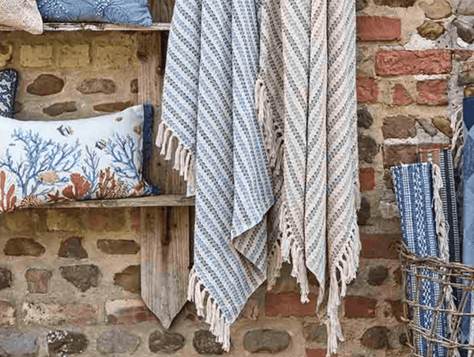 Textile items including a towel and pillows against a stone wall.