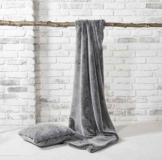 Tipped Faux Fur Throw in Charcoal by Walton & Co. hanging on a branch.